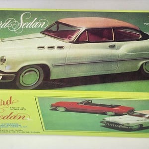 Pode incluir: Uma caixa retangular de papelão verde para um carro de brinquedo rotulado como Standard Sedan. A caixa apresenta uma ilustração de um carro vintage na cor creme com teto bege, texto lendo Friction Powered With Sound Effects e Made In China.