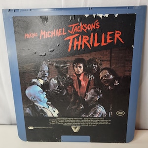 May include: A blue plastic case for the Making Michael Jackson's Thriller CED video disc. The cover features a graphic of Michael Jackson surrounded by zombies, with the title in red text and additional descriptive text printed at the bottom.