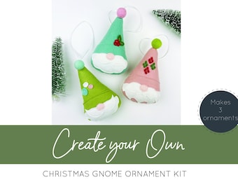 Puede incluir: Un kit de manualidades para crear tres adornos de gnomo navideños de fieltro. El kit incluye piezas de fieltro en verde, rosa y azul, con fieltro blanco para las barbas. Los gnomos tienen sombreros y caras de diferentes colores, con pequeños detalles como bayas y lunares. El texto de la imagen dice "Crea tu propio kit de adornos de gnomo navideño" y "Hace 3 adornos".