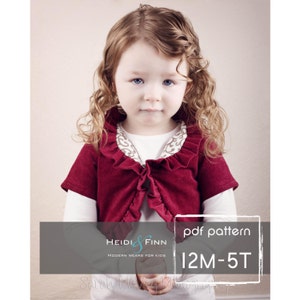 Puede incluir: Un cárdigan rojo con ribete de volantes blancos y una camisa blanca de manga larga debajo. El cárdigan es para niños y tiene un patrón pdf para las tallas 12M-5T. El texto "Heidi & Finn Modern Wears for Kids" está en la parte inferior izquierda de la imagen. El texto "pdf pattern 12M-5T" está en la parte inferior derecha de la imagen.