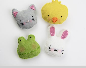 May include: Four felt mini plush animal toys: a gray cat, a yellow chick, a white bunny, and a green frog. The toys are arranged in a square pattern on a white background. The text "Spring Time minis" is below the toys.