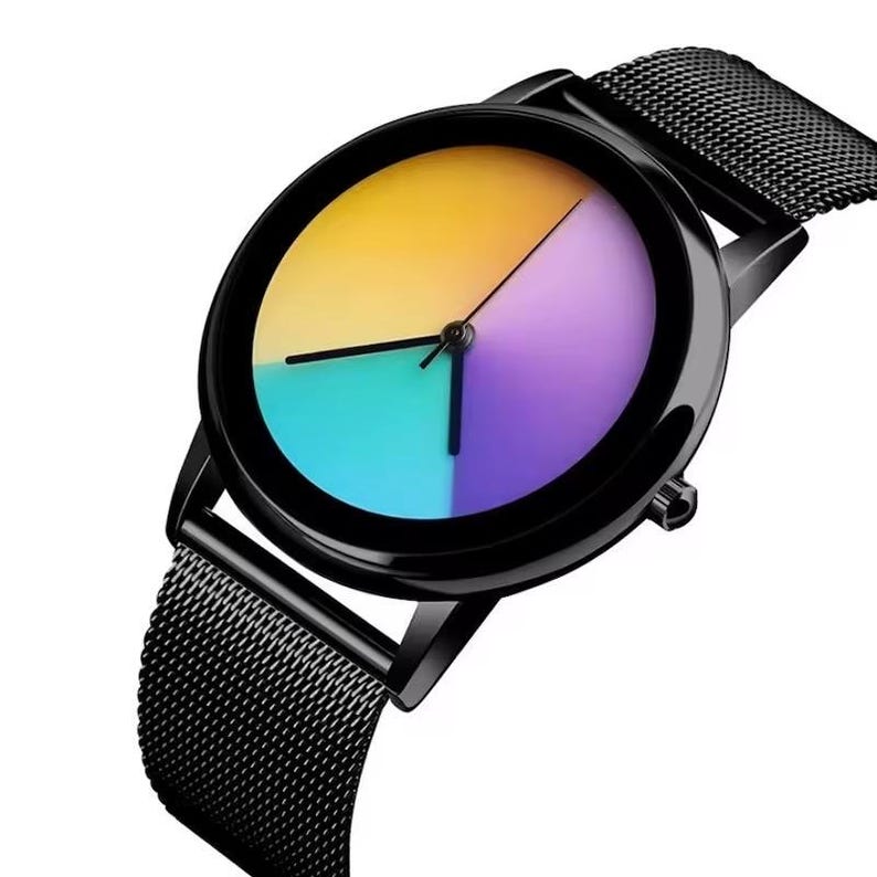 May include: Black wristwatch with a round face divided into four sections of color: yellow, purple, teal, and blue. The watch has a black mesh band and black hands. The watch face is approximately 1.5 inches in diameter.