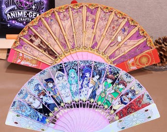 Può includere: Due ventagli pieghevoli rosa con disegni di personaggi anime colorati. Il ventaglio superiore presenta un design dorato e viola su sfondo bianco. Il ventaglio inferiore presenta un design blu e bianco su sfondo rosa.