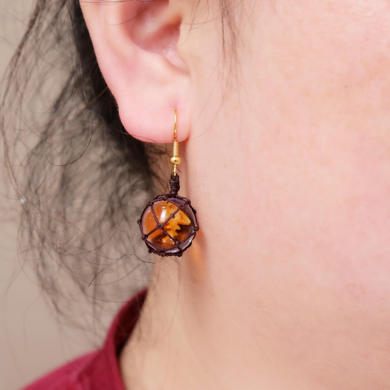 Close-up image of the handmade Splatoon-themed resin earrings, highlighting the fine detail of the fish egg texture, the reflective quality of the golden-orange resin, and the intricately woven mesh netting. The gold-plated copper hook is visible, showing the polished finish and how it complements the amber resin. This product shot emphasizes the quality and creativity of the design, ideal for Etsy shoppers searching for fandom earrings, gamer girl jewelry, or unique handmade accessories.