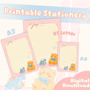 Op de afbeelding: Roze printbaar briefpapier met de tekst "Printable Stationery" en "Digital Download". De set bevat A5, US Letter en A6 notitieblokken met een teddybeer- en dinosaurusontwerp. De notitieblokken hebben de tekst "Stay Kind".