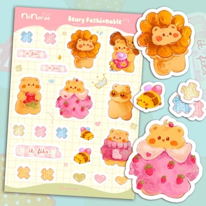 Op de afbeelding: Een vel stickers met het thema "Beary Fashionable". De stickers tonen cartoonberen in verschillende outfits, waaronder een leeuwenmanen, een aardbeienjurk en een trui. Extra stickers zijn onder andere bijen en pleisters.