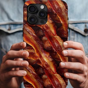 Könnte beinhalten: Eine Smartphone-Hülle mit einem Nahaufnahmebild von gebratenem Speck. Die Hülle zeigt Streifen knusprigen Specks in Rot-, Braun- und Gelbtönen. Die Handyhülle hat ein schwarzes Kameramodul.