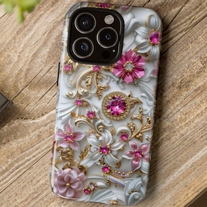 Peut inclure: Coque de téléphone blanche avec un motif floral orné de fleurs roses, d'accents dorés et de pierres précieuses roses incrustées. L'étui a un aspect en relief en trois dimensions et une finition brillante.