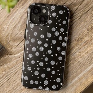 May include: Black phone case with a silver glitter polka dot pattern.
