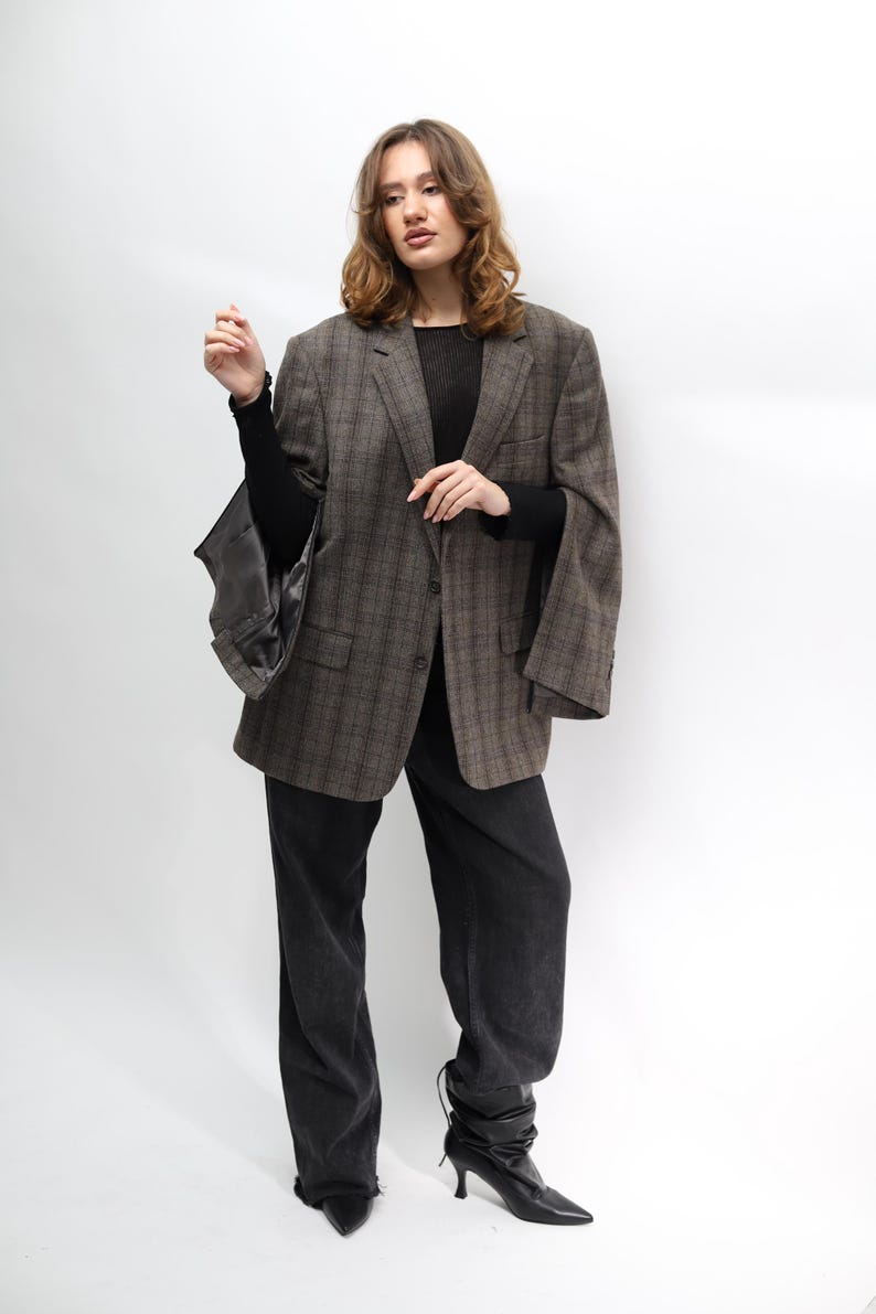 May include: A brown plaid blazer, black top, and dark wash jeans. The blazer features a classic check pattern and a relaxed fit. The jeans are a straight-leg style. The outfit is completed with black heeled boots.