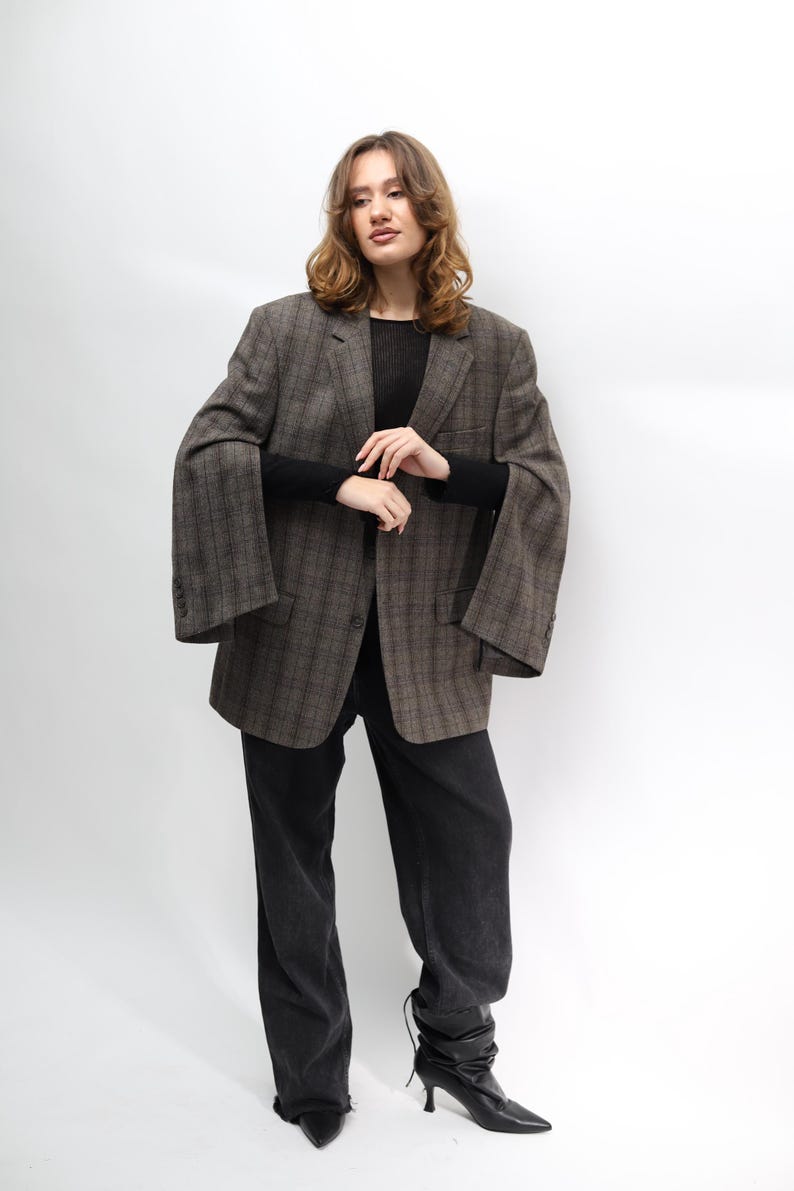 May include: A brown plaid blazer with wide sleeves, worn with black trousers and boots. The blazer features a classic check pattern and a relaxed fit. The outfit is completed with a black long-sleeve top.