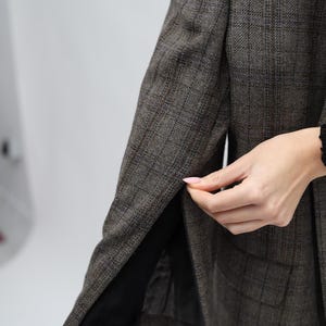 May include: A brown plaid blazer with a black lining. The blazer features a classic design with a notched lapel and a two-button closure. The fabric has a subtle texture and a muted colour palette.