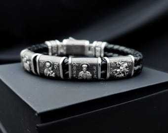 Pulseira de prata com imagens dos Santos Miguel, Maria, Nicolau, Jorge e uma oração, com acabamento em couro preto.