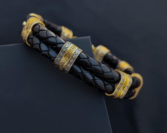 Uma pulseira com elegantes e robustas inserções de prata, com acabamento em banho de preto, banho de ouro e couro.