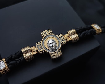 Uma pulseira de prata com imagens de Jesus, São Miguel, Santa Maria, São Nicolau e São Jorge, feita de couro escurecido.