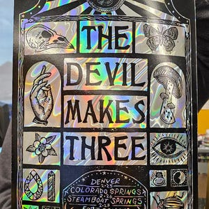 May include: Black and silver poster with the text "THE DEVIL MAKES THREE" and various illustrations. Includes tour dates for Denver, Colorado Springs, Steamboat Springs, Fort Collins, and Boulder.