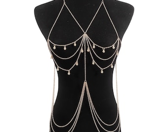May include: Gold-colored body chain with a halter-style neckline and multiple cascading strands. The chain features small, dangling embellishments and is displayed on a black mannequin. This piece is designed to be worn over clothing or directly on the skin.
