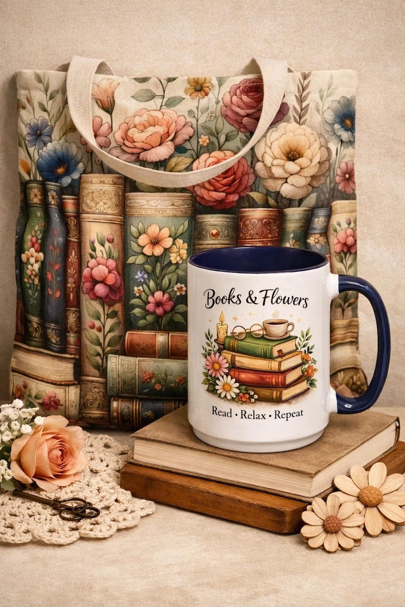 a white mug with a floral design, a stack of books, a tote bag with a floral pattern, and some flowers and a lace doily on a table.