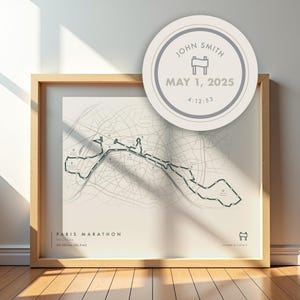May include: A framed print featuring the Paris Marathon route map in muted colours. The text "PARIS MARATHON" and the distance, 42.195 km, are shown. A circular emblem displays "JOHN SMITH" and "MAY 1, 2025".