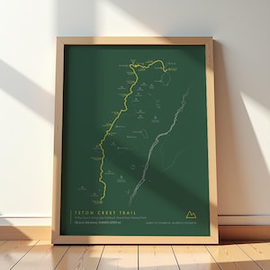 May include: A framed map print of the Teton Crest Trail in Grand Teton National Park. The dark green background features a yellow highlighted trail path, white topographical lines, and text stating 39.0 mi (62.8 km) and 9,045 ft (3757 m).