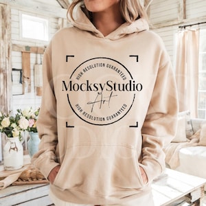 May include: A beige hoodie with a black circle logo that says "MocksyStudio Art" and "High Resolution Guaranteed" around the circle. The hoodie is being worn by a person with their hands in the pockets.