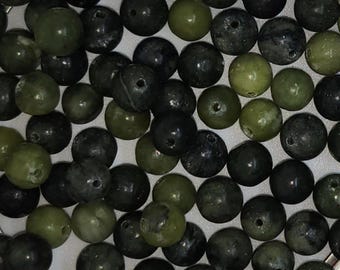 May include: A collection of dark green and black round beads. The beads are made of a smooth, polished stone.
