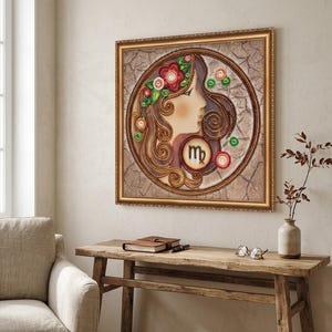 May include: A square framed wall art piece featuring a profile illustration of a woman with long, swirling brown hair adorned with red and green floral accents. A circular emblem containing the Virgo zodiac symbol is centered below.