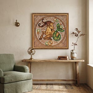 May include: A square framed wall art piece featuring a circular illustration of the Capricorn zodiac sign. The artwork depicts a tan goat with a green fish tail, surrounded by small circular patterns on a textured, cracked beige background.
