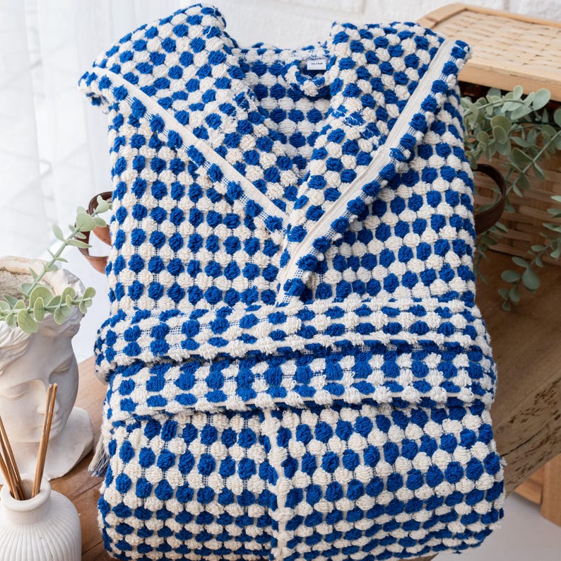 May include: A blue and white hooded bathrobe with a waffle-like texture. The robe has a zipper closure and a checkered pattern.