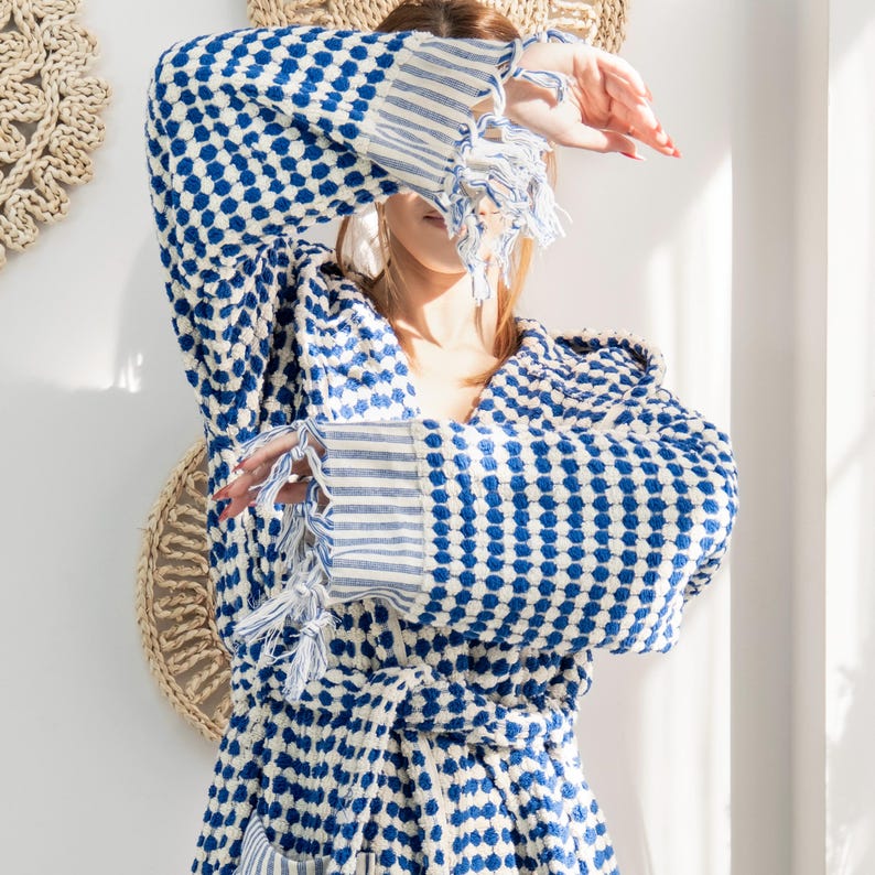 May include: A blue and white patterned robe with a hood and a tie belt. The robe is made of a soft, textured fabric.