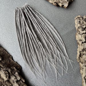May include: A set of grey synthetic dreadlocks with silver beads.