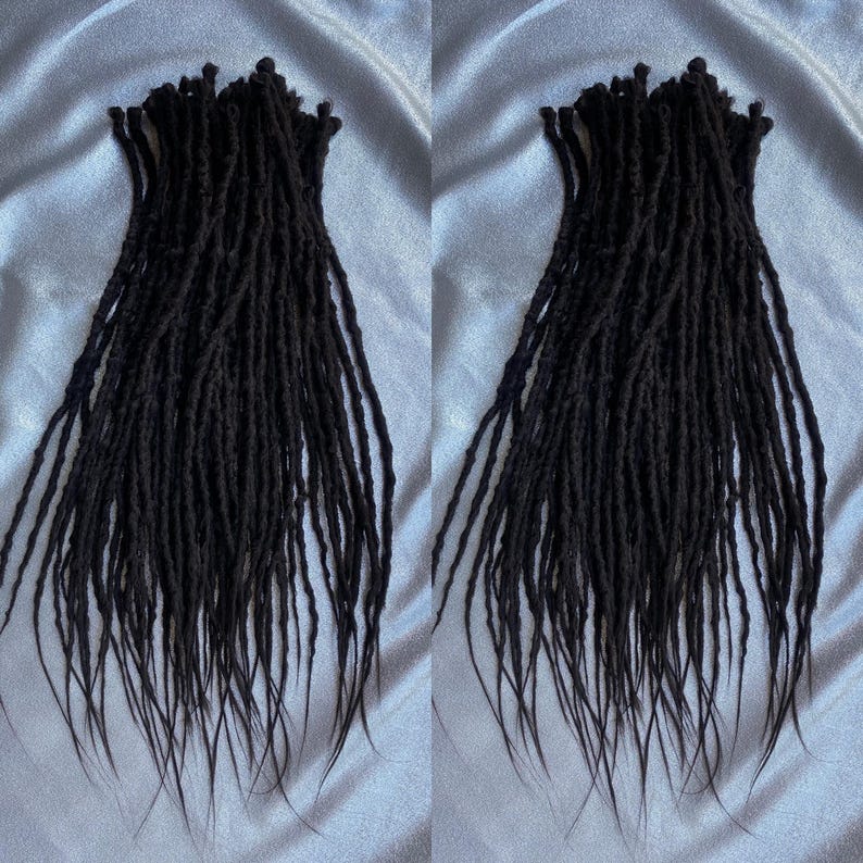 May include: Two sets of black synthetic dreadlocks, each set containing approximately 50 dreads. The dreadlocks are long and straight, with a slightly textured surface.