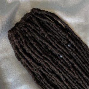 May include: Black dreadlocks with black beads. The dreadlocks are long and thick, and the beads are evenly spaced throughout.