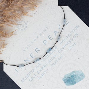 May include: A delicate necklace featuring light blue aquamarine stones and a black cord. The necklace is presented on a white card with the words "Inner Peace" and a list of affirmations. The card also includes the text "Free Gift for Every Purchase" and "Save More on Matching Sets! Buy 2 or 3 Items Set & Get Extra 5% or 10% Off*"