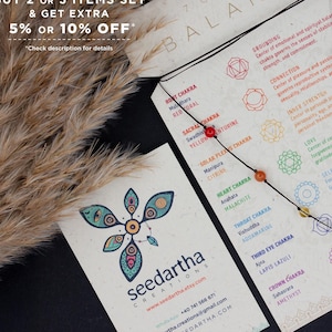 May include: A 7 chakra bracelet with colourful beads on a black cord. The bracelet is laid out on a card with a chart of the 7 chakras and their corresponding colours. The card also includes an affirmation for each chakra. The card is made from recycled paper and has a natural, earthy feel.