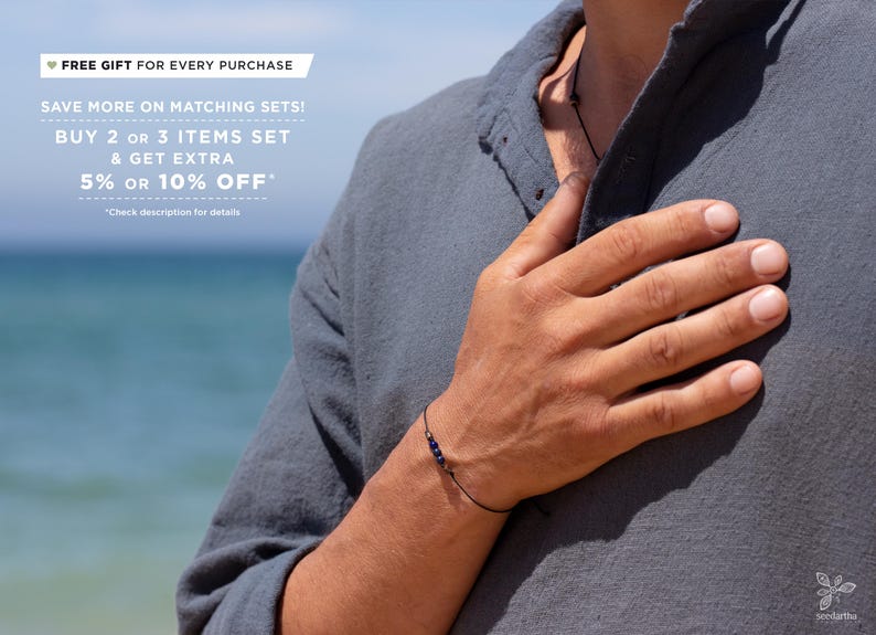 May include: A person wearing a dark gray shirt with a black cord necklace and a black string bracelet with small blue beads. The text "FREE GIFT FOR EVERY PURCHASE" is at the top of the image. The text "SAVE MORE ON MATCHING SETS! BUY 2 OR 3 ITEMS SET & GET EXTRA 5% OR 10% OFF*" is below the first line of text. The text "*Check description for details" is below the second line of text.