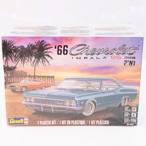May include: A Revell model kit box featuring a light blue '66 Chevrolet Impala SS 396 car. The box art depicts the car on a beach with palm trees and a sunset. The box includes the text "1 Plastic Kit".