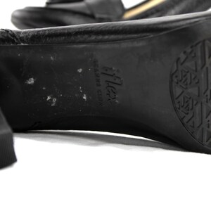 May include: Close-up of a black leather heeled shoe. The sole features a textured pattern and the brand name "iFlex". The heel is thick and square. The shoe is on a white background.