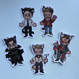 May include: Five cartoon stickers featuring characters with animal ears. One sticker depicts a character in a suit and tie, another in a red jacket, and a third in a bat costume. The remaining two stickers show characters holding a hammer and an axe.