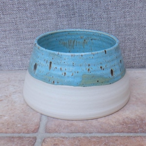 Puede incluir: Un cuenco de cerámica hecho a mano con un diseño de dos tonos. La mitad superior es azul claro moteado, mientras que la mitad inferior es de color blanco crema. El cuenco tiene una abertura ancha y una base redondeada, adecuado para la decoración del hogar.