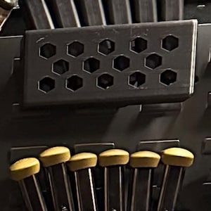 May include: Two rows of black holders with hexagonal holes, each holding a set of six tools. The top row holds six green tools, and the bottom row holds six yellow tools.