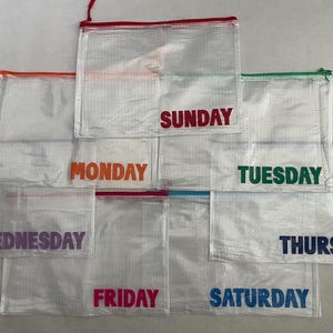 May include: Clear, zippered pouches with the days of the week printed in various colors. Each pouch has a colored zipper and the days of the week are printed in a corresponding color. Great for organizing documents or supplies.