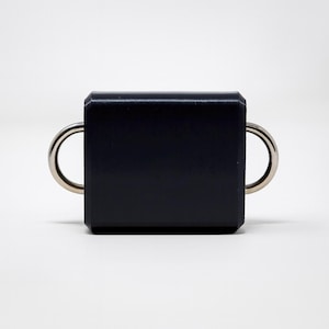 May include: A dark navy blue, rectangular object with two silver-colored, semi-circular handles. The object has a smooth, matte finish and is set against a plain white background. The design is minimalist and modern.