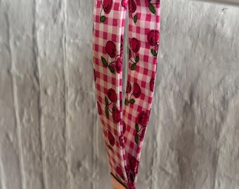 Op de afbeelding: Een roze en witte gingham sleutelhanger met een kersenprint en een gouden sleutelring.