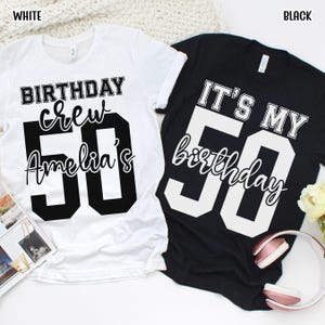 May include: A white t-shirt with black text reading BIRTHDAY crew Amelia's 50 and a black t-shirt with white text reading IT'S MY 50 birthday. Both shirts feature a crew neck, short sleeves, and large block-style numbers for the age 50.