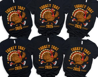May include: Black t-shirts with a cartoon turkey wearing sneakers and the text "TURKEY TROT 2025". The turkey has brown feathers, a red wattle, and is running. The text "TURKEY TROT" is in orange.