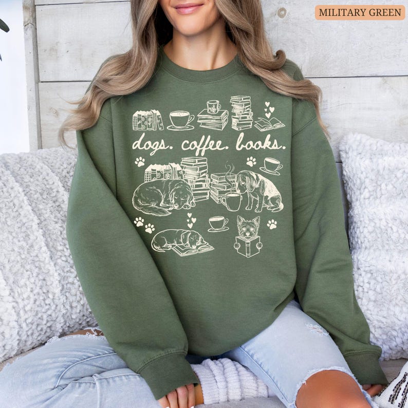 May include: Military green sweatshirt with a white graphic design featuring dogs, books, coffee cups, and the text "dogs. coffee. books." The design includes paw prints and illustrations of dogs reading.