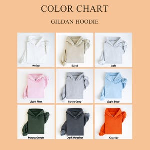 May include: Color chart of Gildan hoodies in various colors. The chart displays hoodies in white, sand, ash, light pink, sport grey, light blue, forest green, dark heather, and orange. Each hoodie is neatly folded, showcasing the color options.