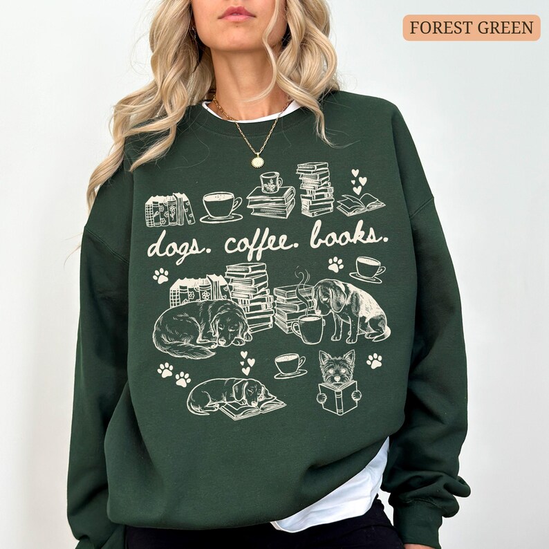 May include: Forest green sweatshirt with the words "dogs. coffee. books." and illustrations of dogs, books, and coffee cups. The design is in white. The sweatshirt has a white collar.