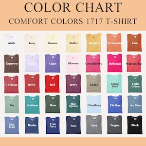 May include: Color chart of Comfort Colors 1717 T-shirts in various colors, including white, ivory, banana, butter, mustard, terracotta, yam, espresso, orchid, violet, blossom, crunchberry, and more. Each shirt is displayed folded, showcasing the available hues.
